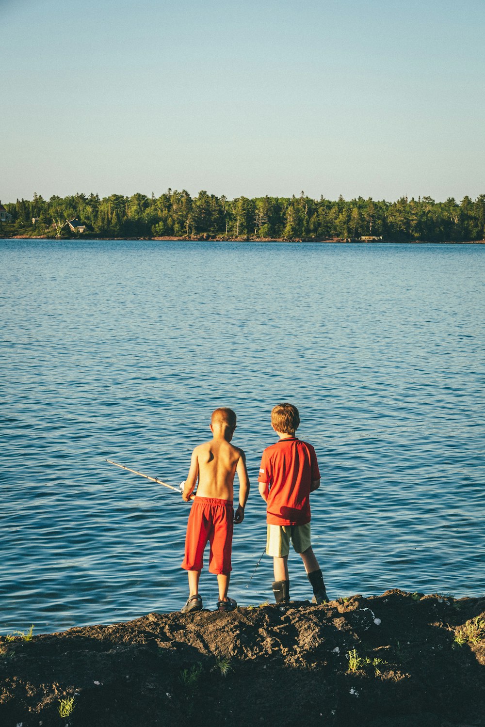 2 boys standing on body of water during daytime