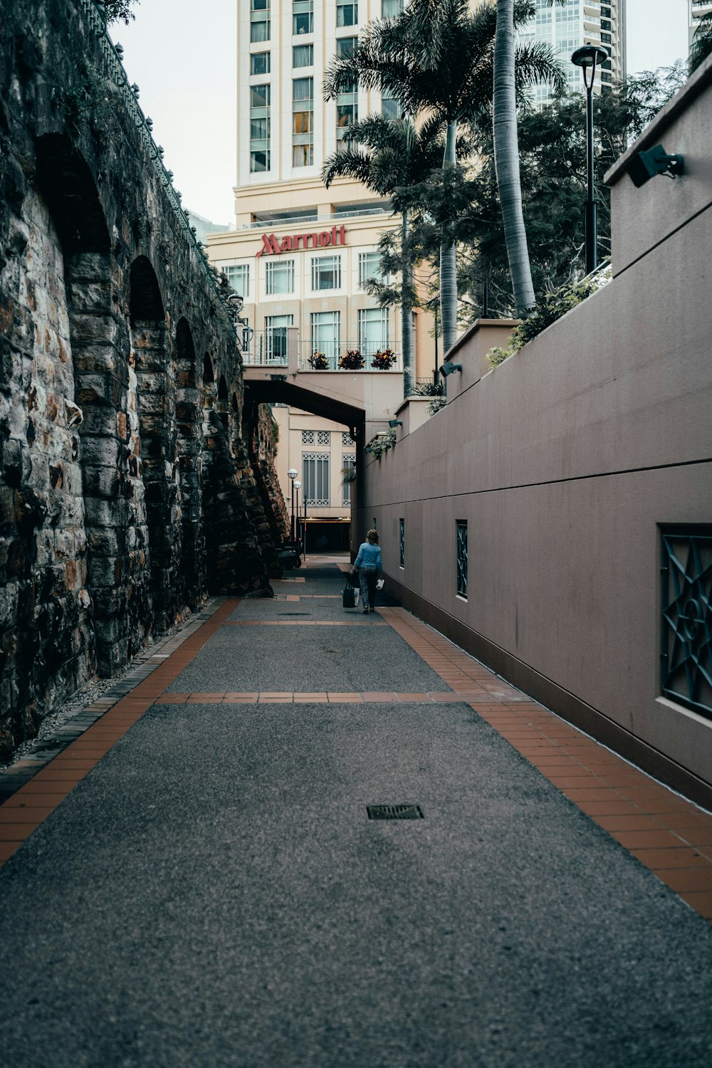 person in blue jacket walking on sidewalk during daytime