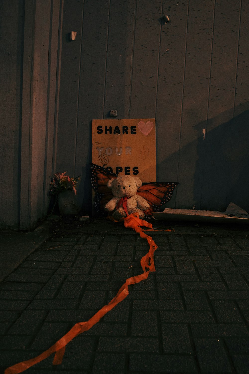 a teddy bear sitting on the ground next to a sign