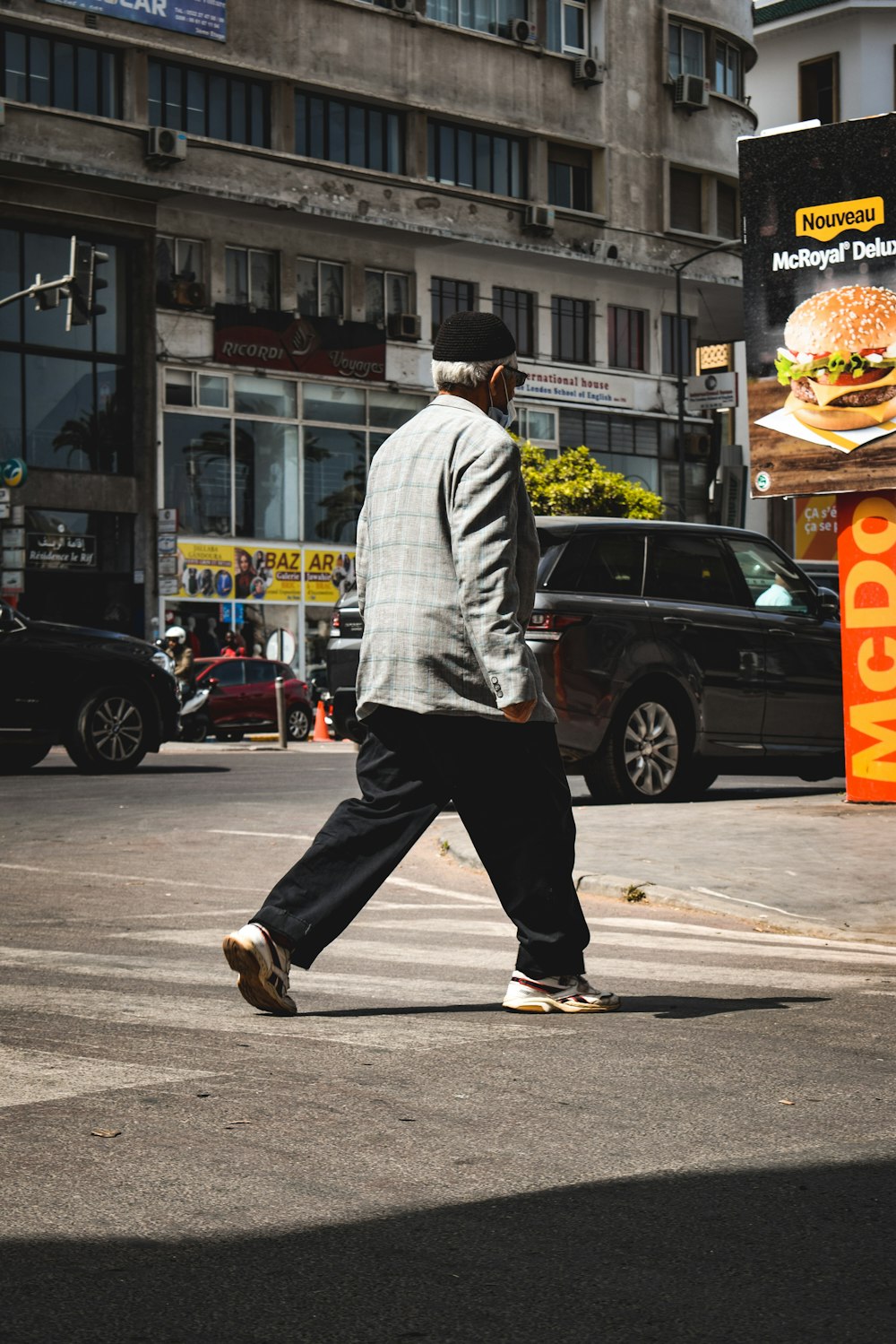 a man walking across a street in front of a burger