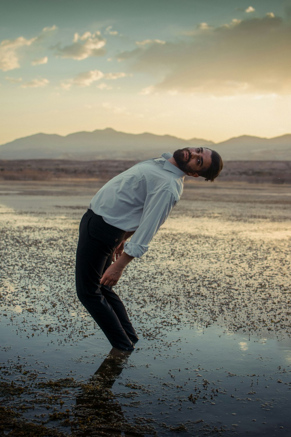 a man in a white shirt and black pants standing in the water