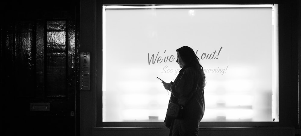 woman in black coat standing near white wall