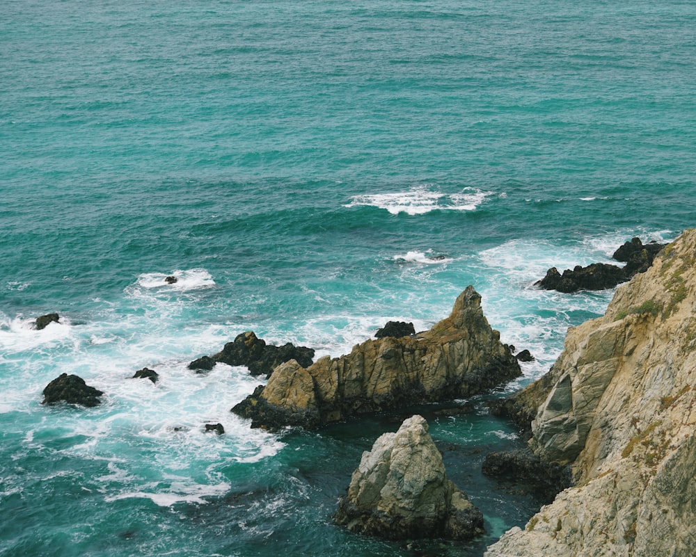 a person sitting on a rock near the ocean