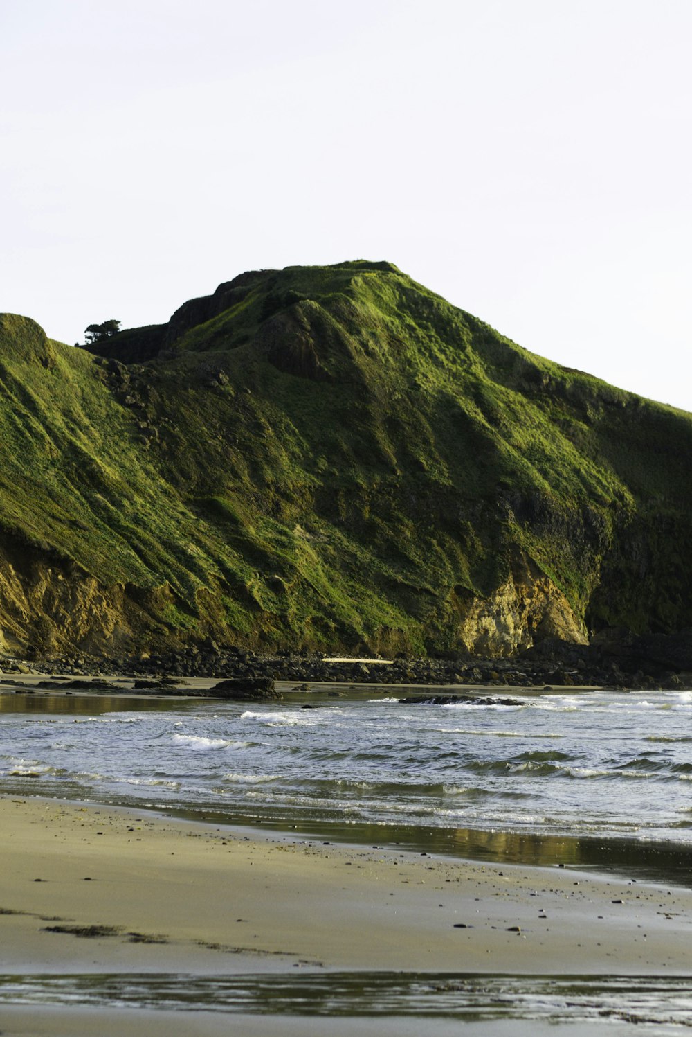 green mountain beside sea during daytime