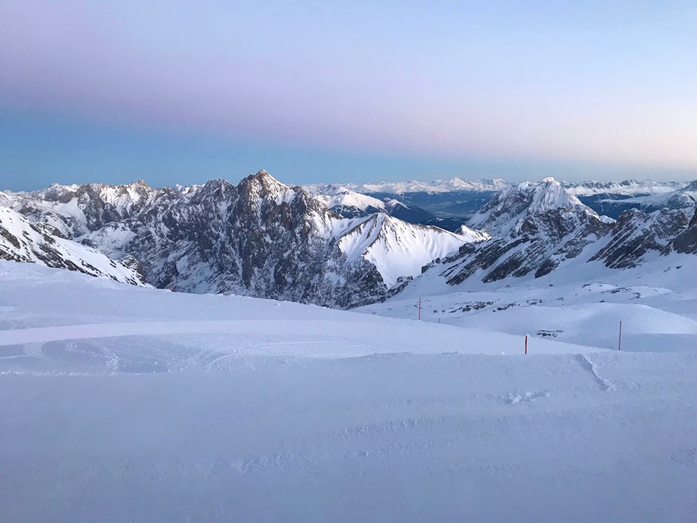 une personne sur des skis debout au sommet d’une pente enneigée