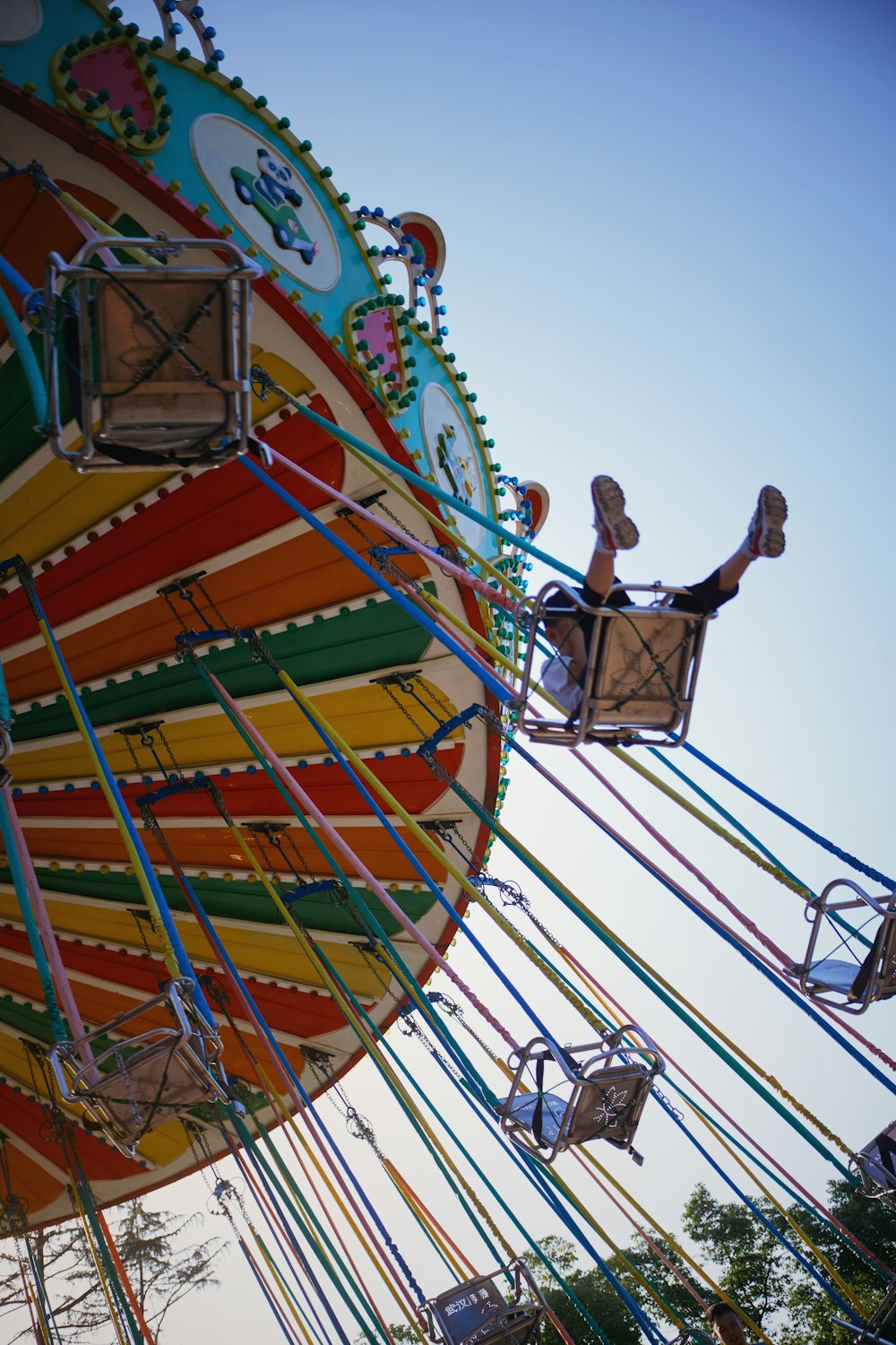 man in black t-shirt and blue denim jeans riding on yellow green and red swing