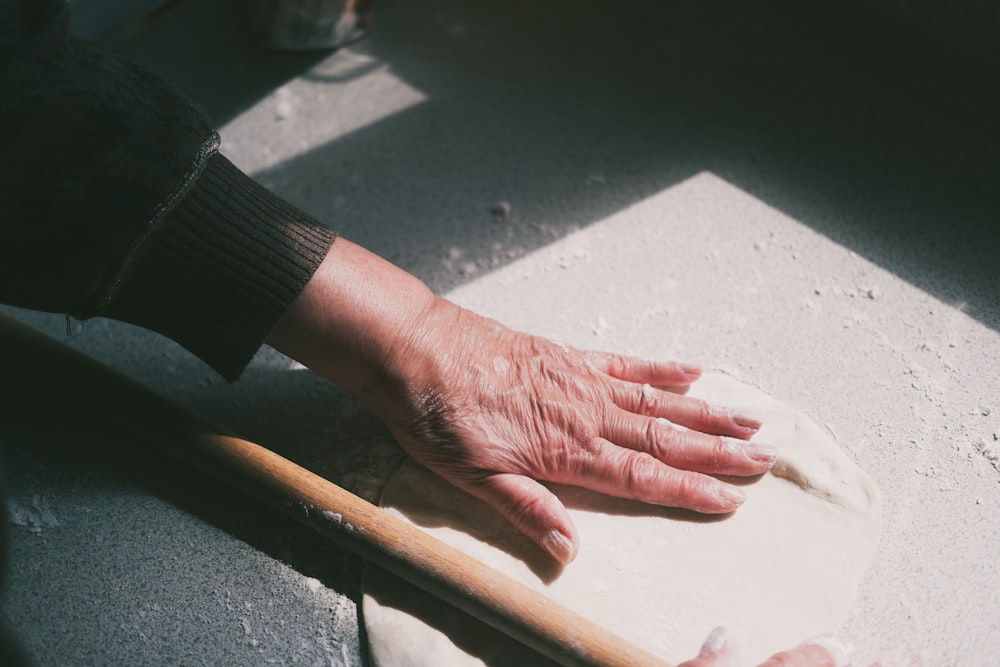 a person's hand on top of a rolling dough