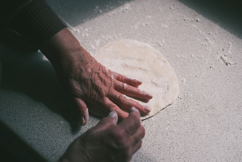 a person's hand on top of a pizza dough