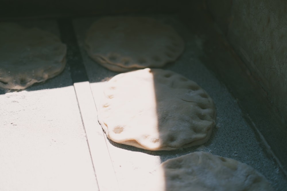 four uncooked pita breads sitting on the ground