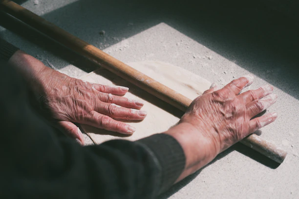 Hands gently shaping dough on a traditional stone surface with soft natural light.