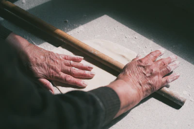 Close-up of hands expertly rolling dough for traditional flatbread in a rustic kitchen.