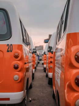 a row of orange and white buses parked next to each other