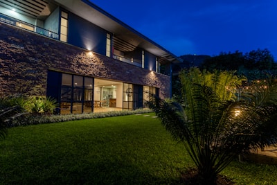 a house with a lawn at night with lights on
