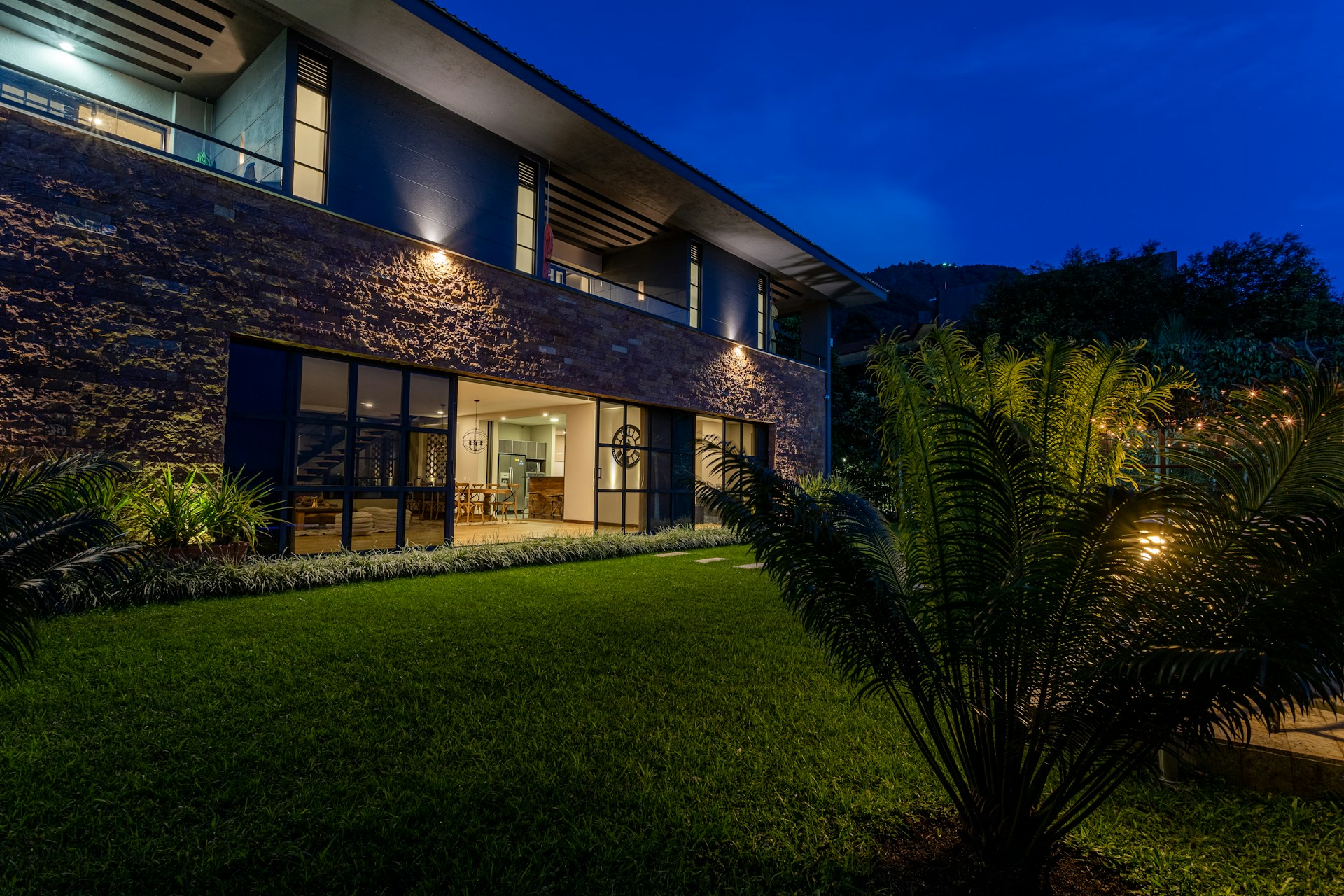 a house with a lawn at night with lights on
