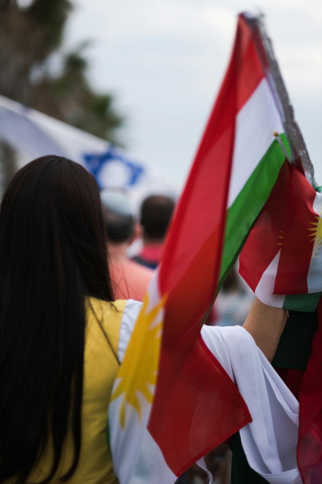 woman in white shirt holding red and yellow flag