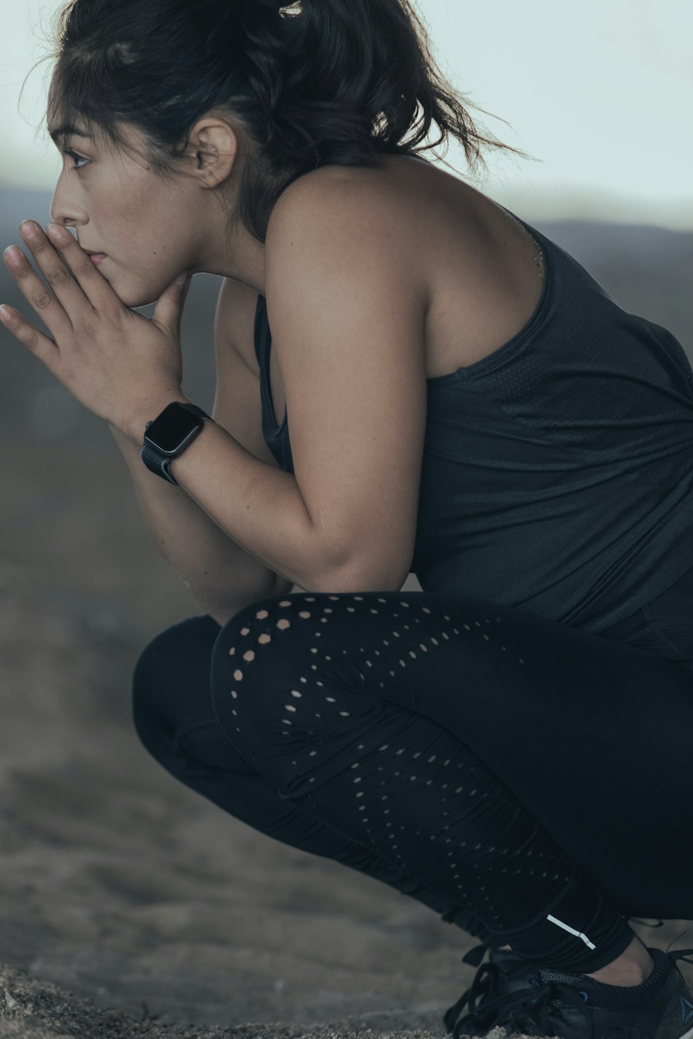 woman in black tank top covering her face with her hand