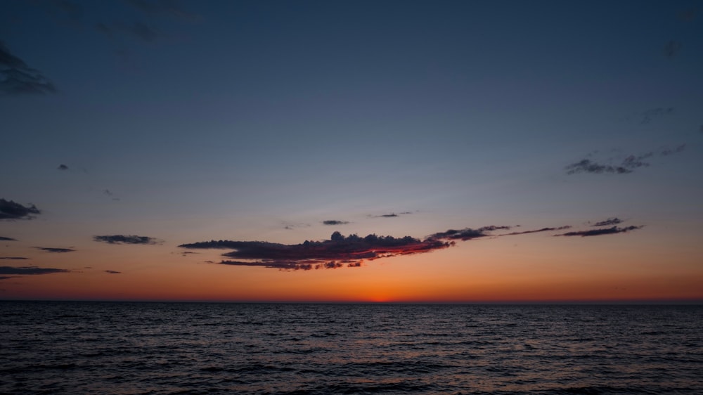 a sunset over the ocean with clouds in the sky