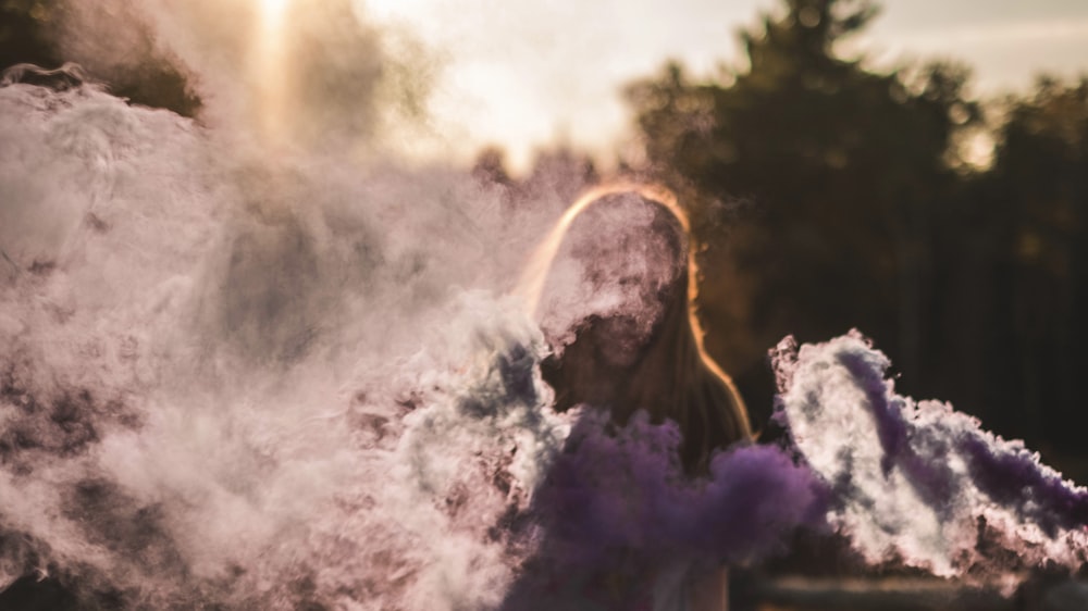 a woman standing in front of a cloud of smoke