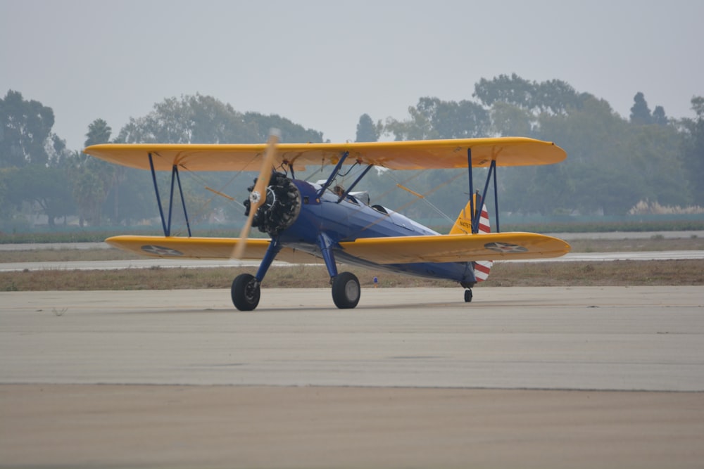 a small blue and yellow airplane on a runway