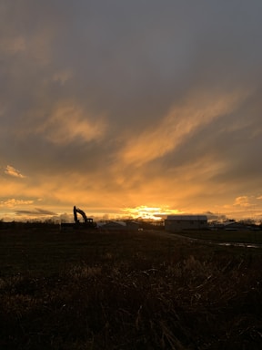 A warm Arizona sunset with hues of orange and purple behind a silhouette of excavation equipment.