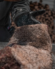 person in black pants and black shoes standing on brown rock