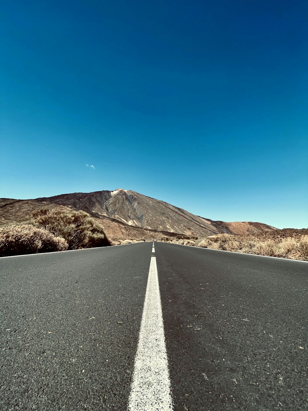 an empty road with a mountain in the background