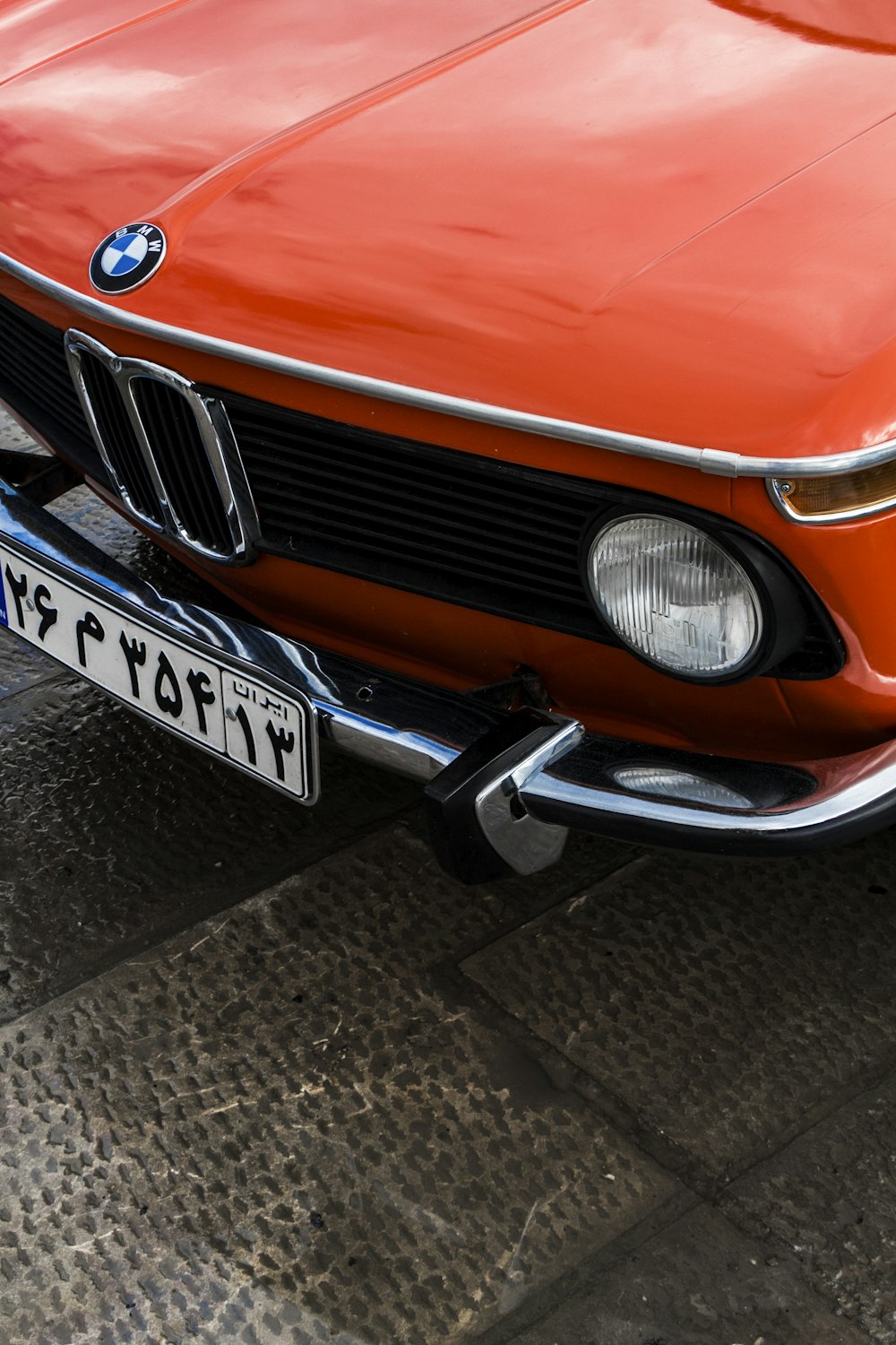 an orange bmw is parked on the side of the road