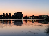A serene cityscape at dusk with modern buildings glowing softly against a deep charcoal sky.