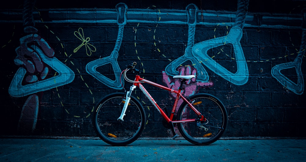 a red bike parked in front of a graffiti covered wall