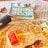 A table covered with a checkered cloth displays a paperback book titled 'All the Bright Places' alongside a deck of Monopoly Deal cards. Nearby, there's a black portable speaker and a pair of sunglasses resting on the table.