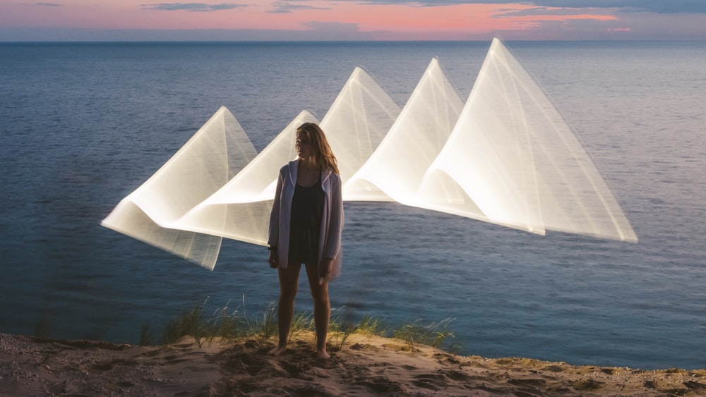 a woman standing on top of a beach next to the ocean