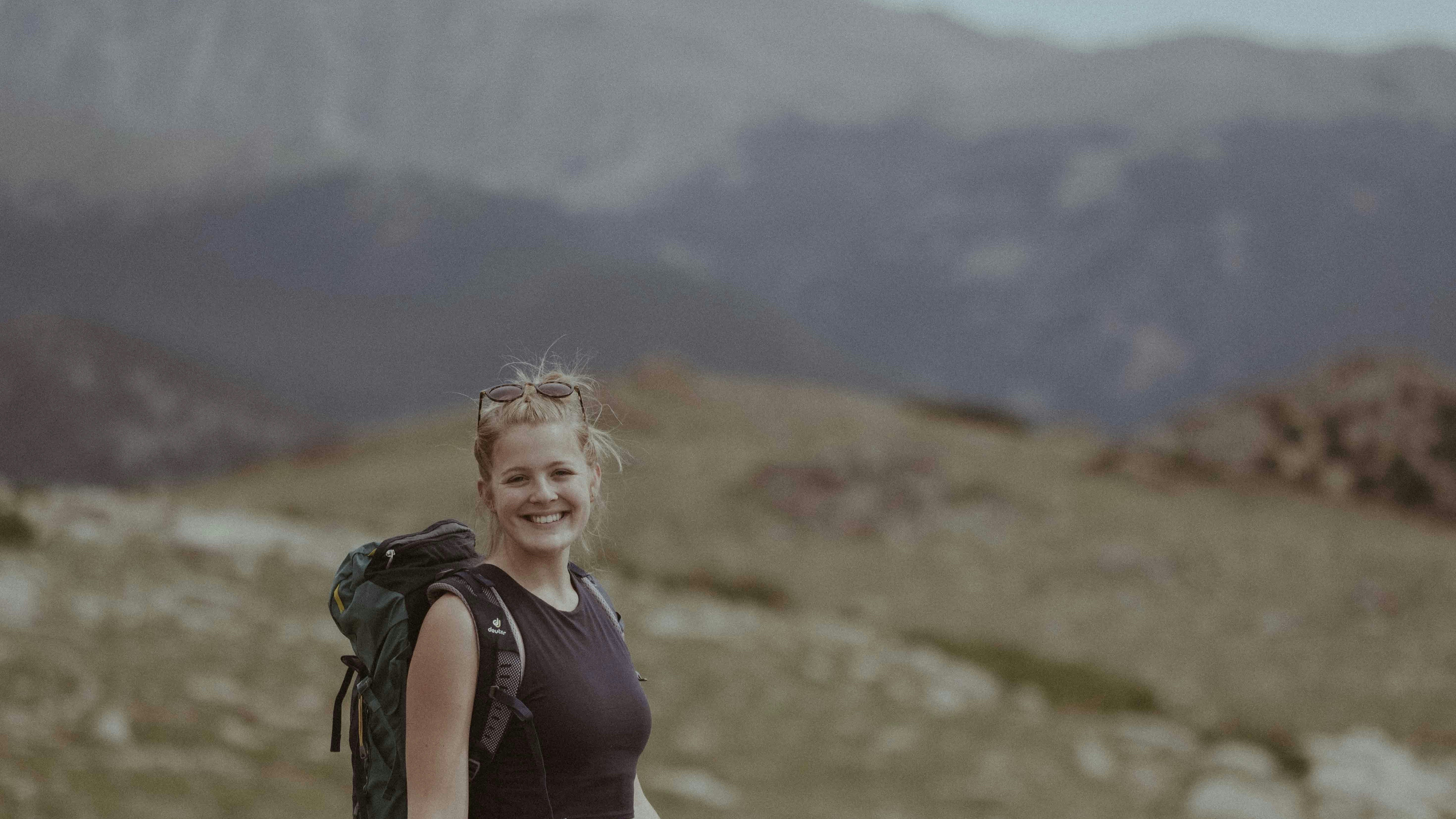 uma mulher com uma mochila no topo de uma montanha