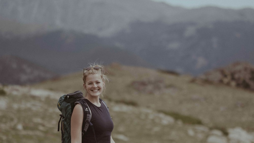 a woman with a backpack on top of a mountain