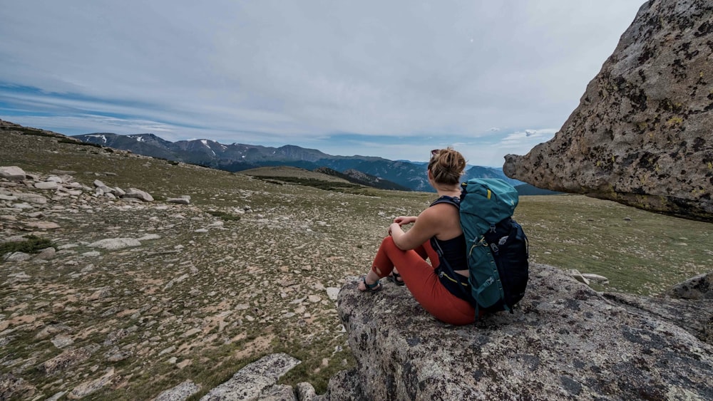 a woman sitting on top of a large rock