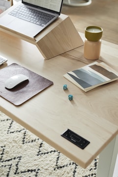 A minimalist workspace with a laptop and sketches on a wooden desk.