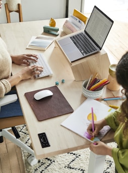 a woman sitting at a table with a child using a laptop