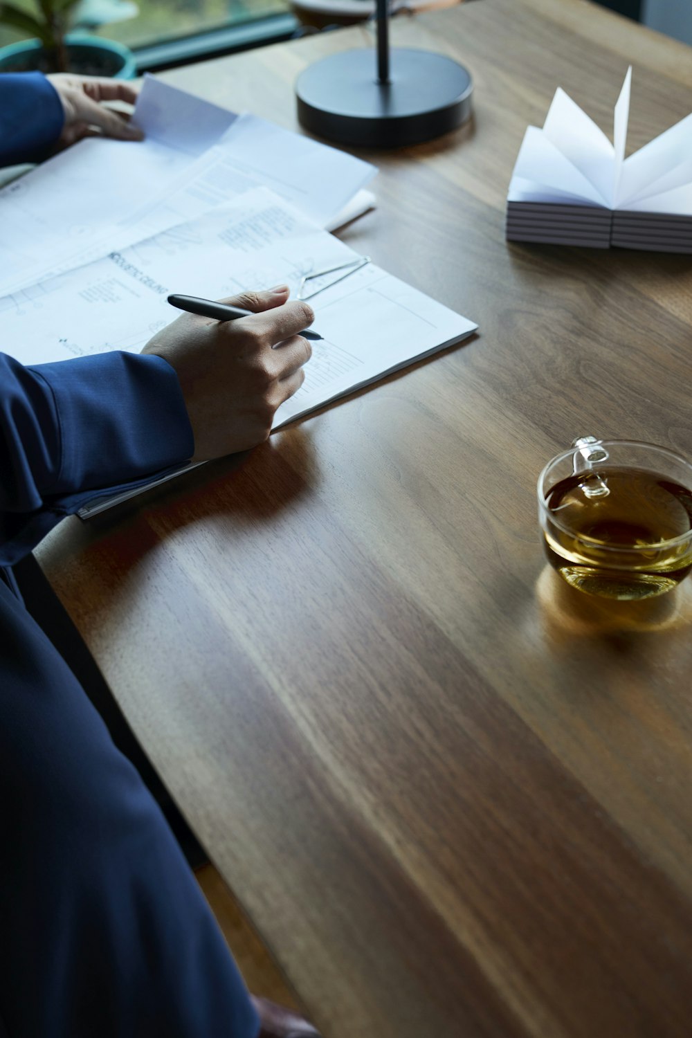 a person sitting at a table writing on a piece of paper