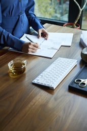 a woman sitting at a desk with a keyboard and papers