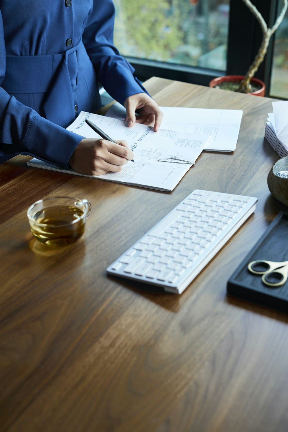 a woman sitting at a desk with a keyboard and papers