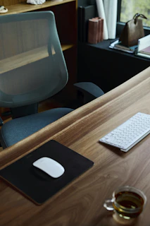 a desk with a computer mouse, keyboard and a mouse pad