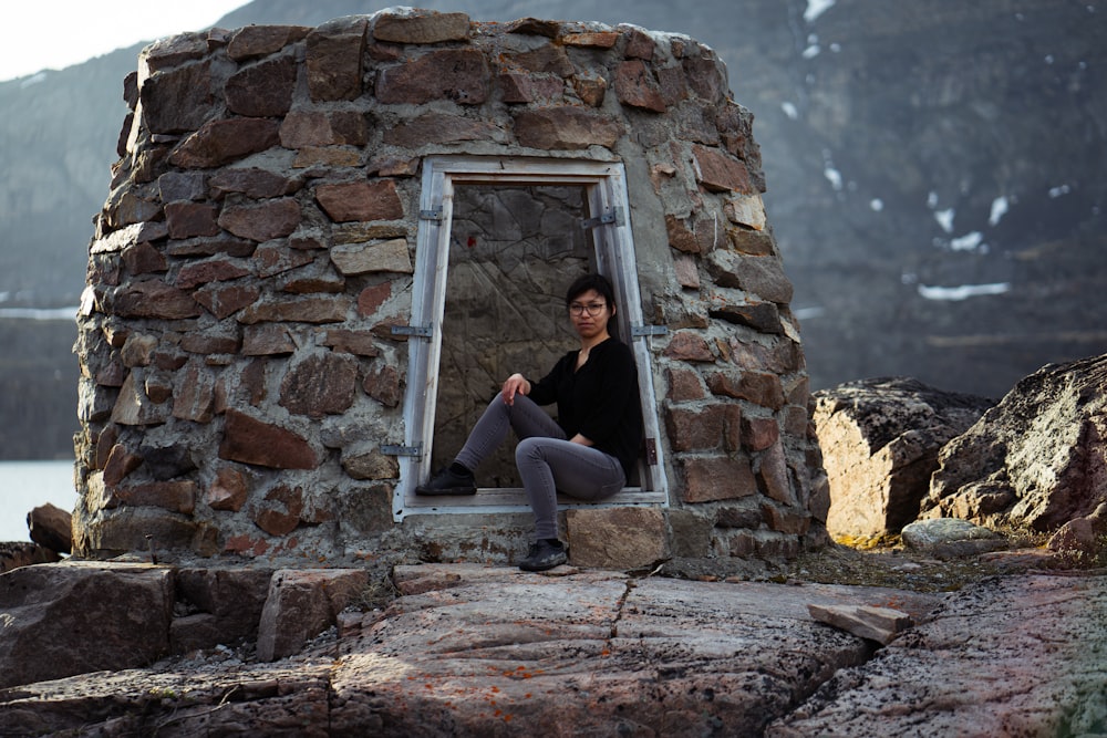 a woman sitting in a window of a stone building