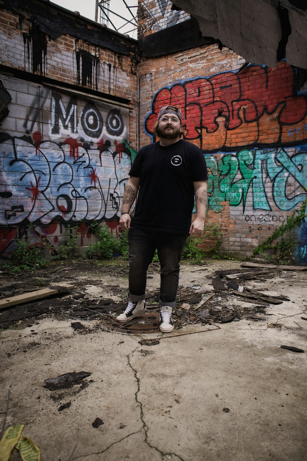 a man standing in front of a graffiti covered wall