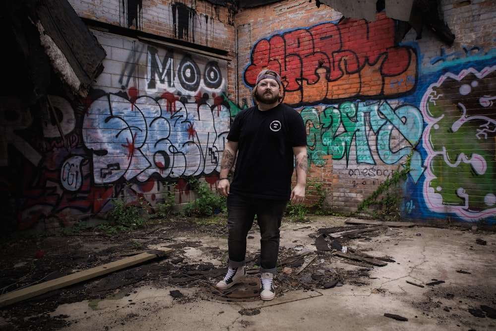 a man standing in front of a graffiti covered wall