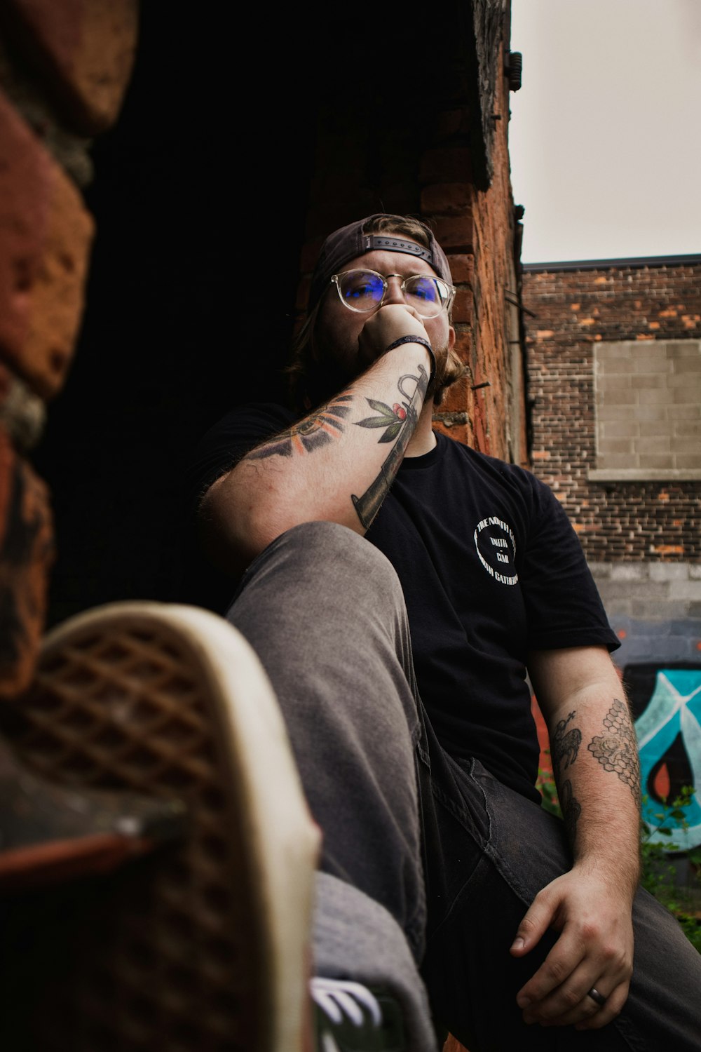 a man with a beard and tattoos sitting in a doorway