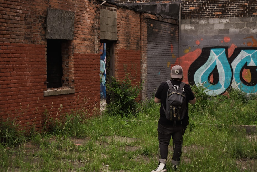 a person with a back pack standing in front of a building with graffiti on it