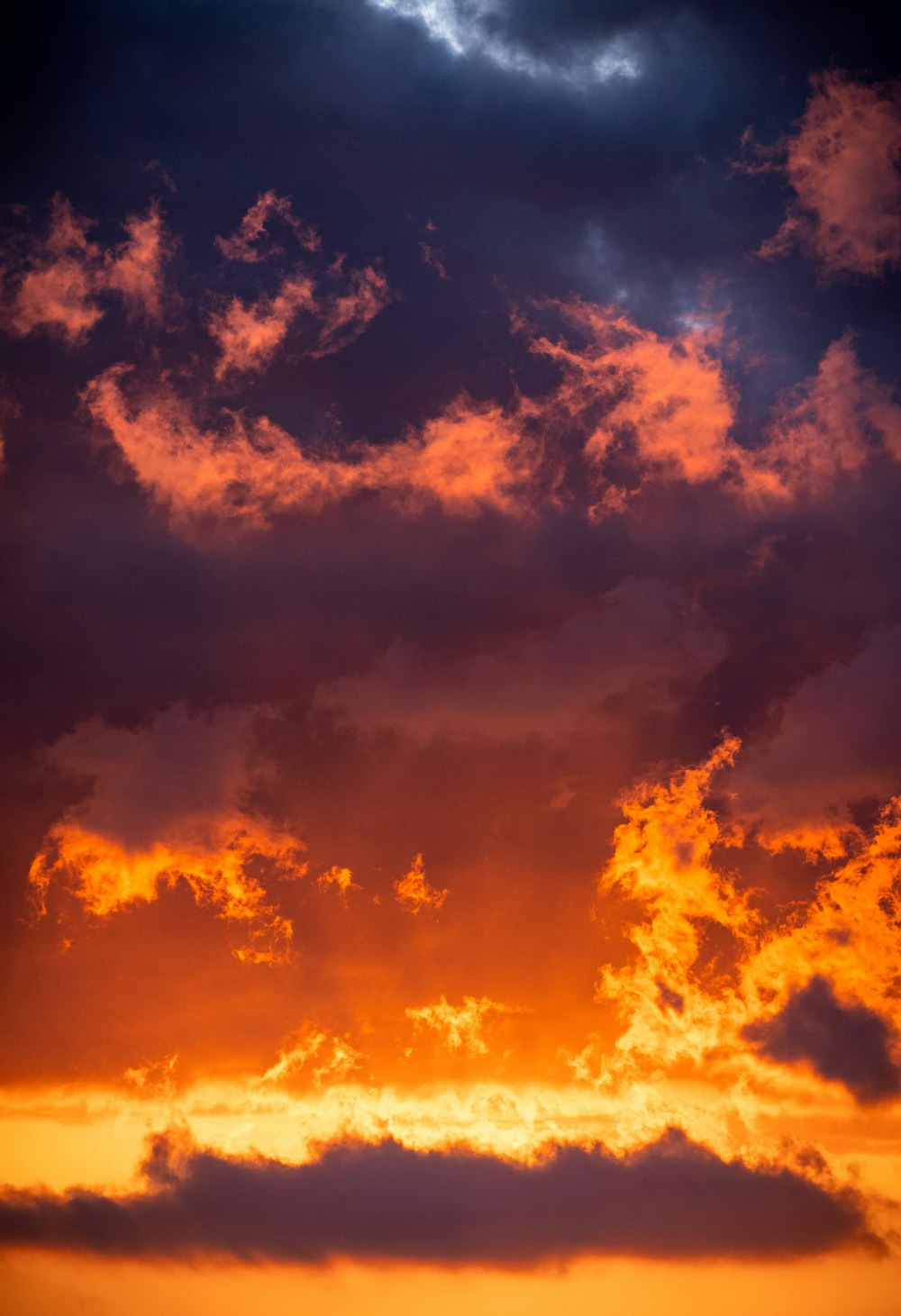 a plane flying through a cloudy sky at sunset