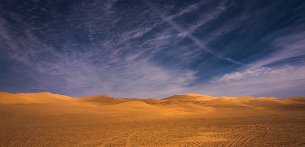 a desert landscape with a blue sky and clouds