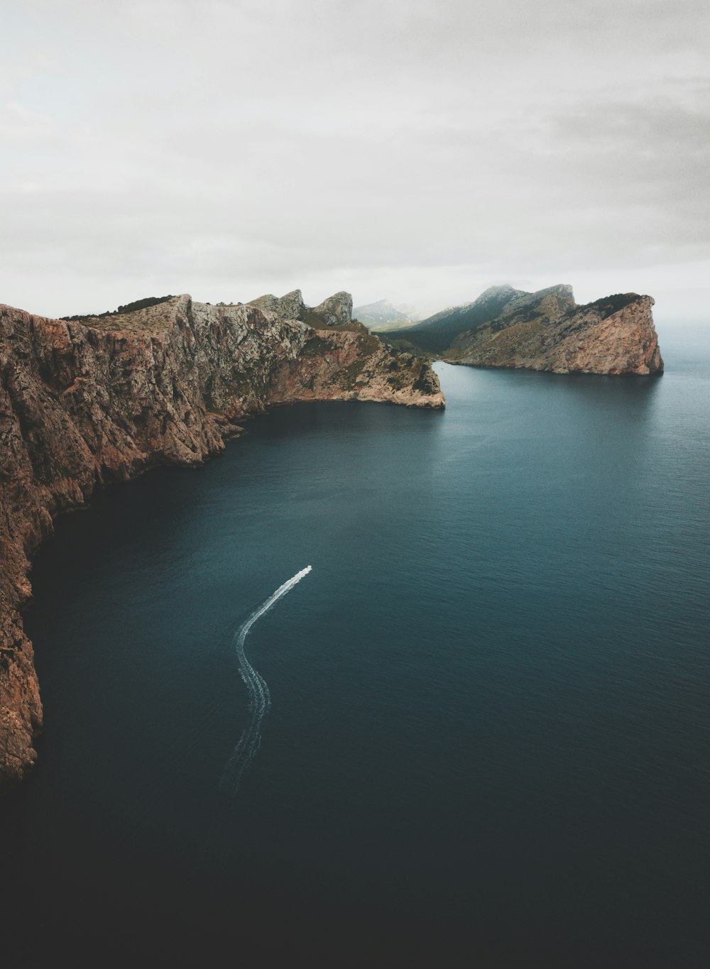 aerial view of a road on a cliff by a lake