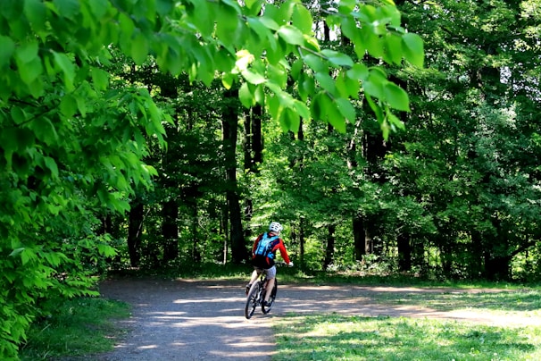 A middle-aged cyclist smiling confidently on a forest trail, surrounded by lush greenery.