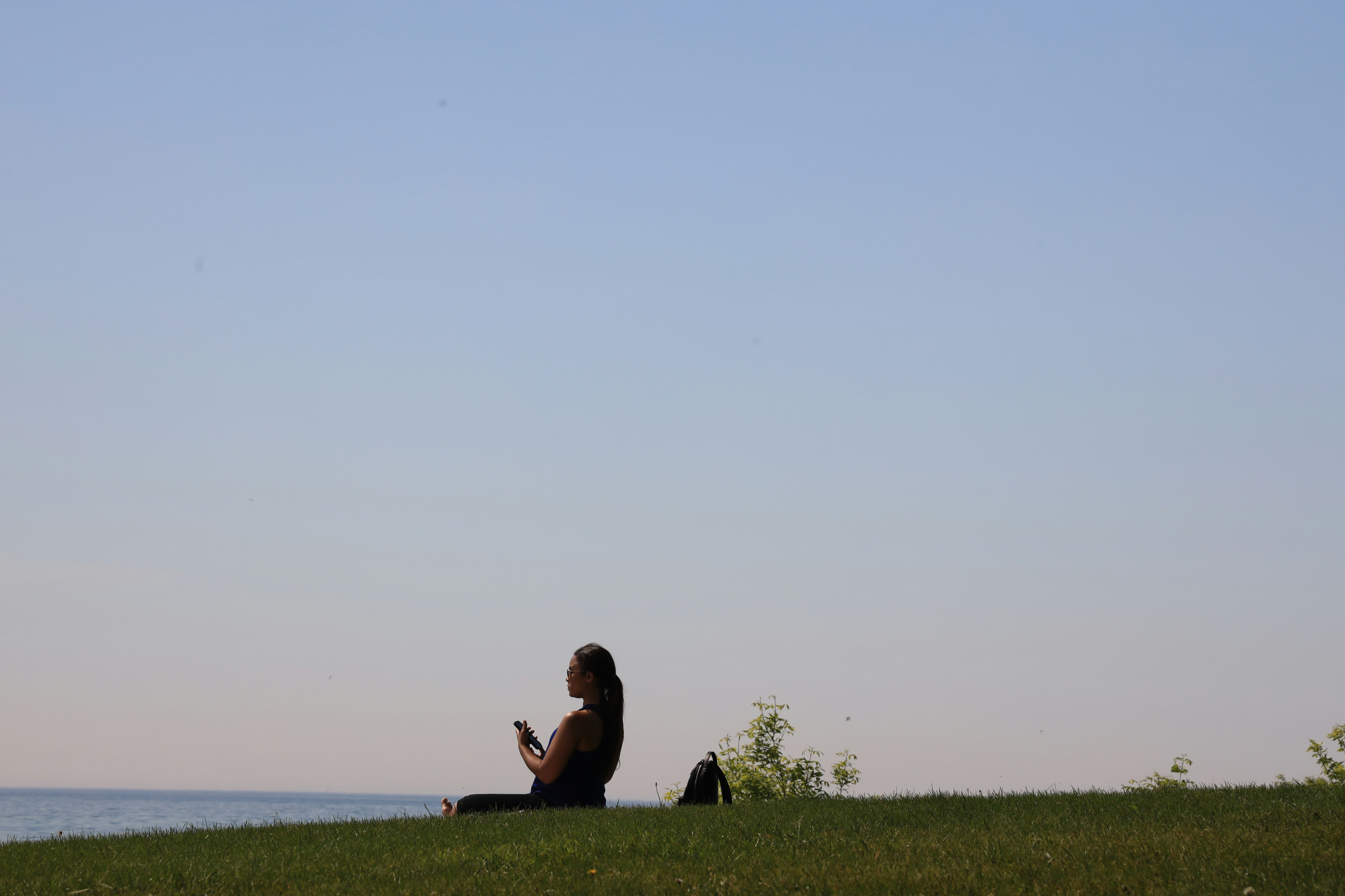 a woman sitting on top of a lush green hillside